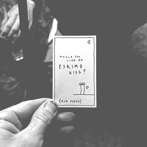 Hand holding a card that says 'Would you like an Eskimo Kiss?'